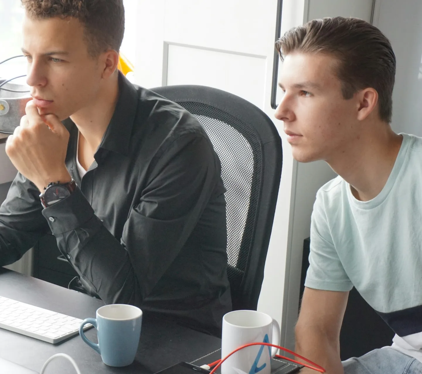 Twee jonge mannen kijken geconcentreerd naar een scherm aan een bureau