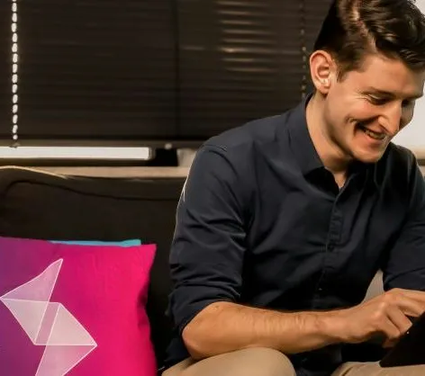 Een lachende man op een bank werkt op een tablet