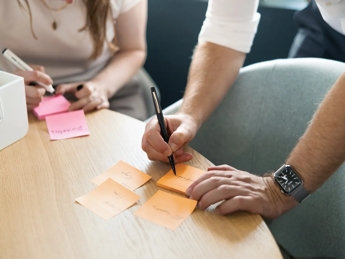 Two colleagues writing ideas on sticky notes during a design session