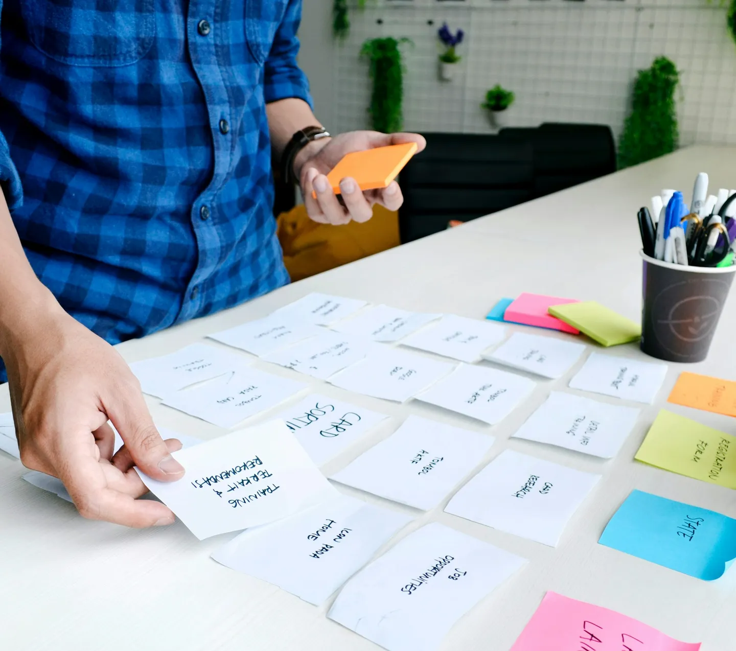 Someone arranging paper cards and sticky notes on a table