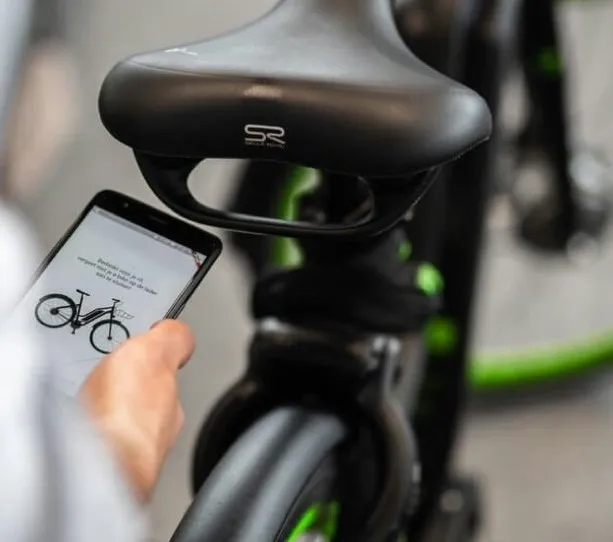 Iemand houdt een telefoon met een fietsapp vast naast een elektrische fiets