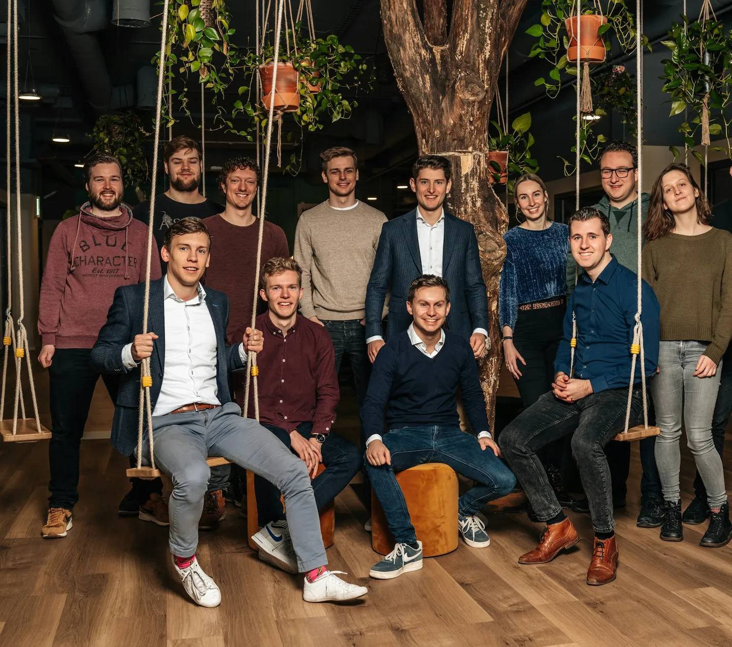 Groepsfoto van een team tussen touwschommels en hangplanten
