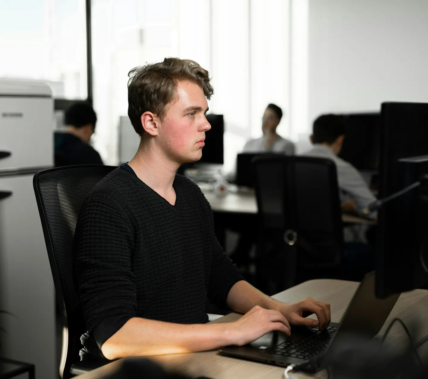 Een ontwikkelaar typt op een laptop in een kantoor