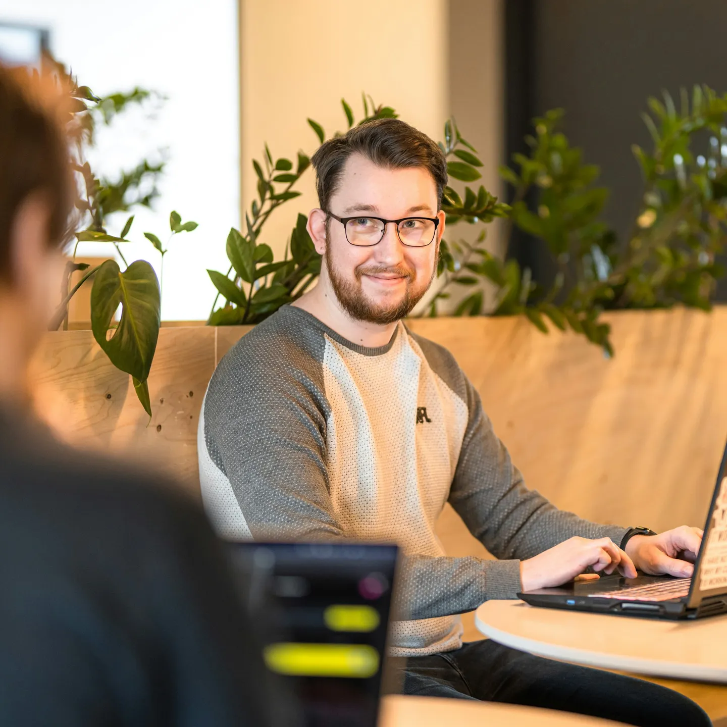 Een man met een bril werkt glimlachend op een laptop