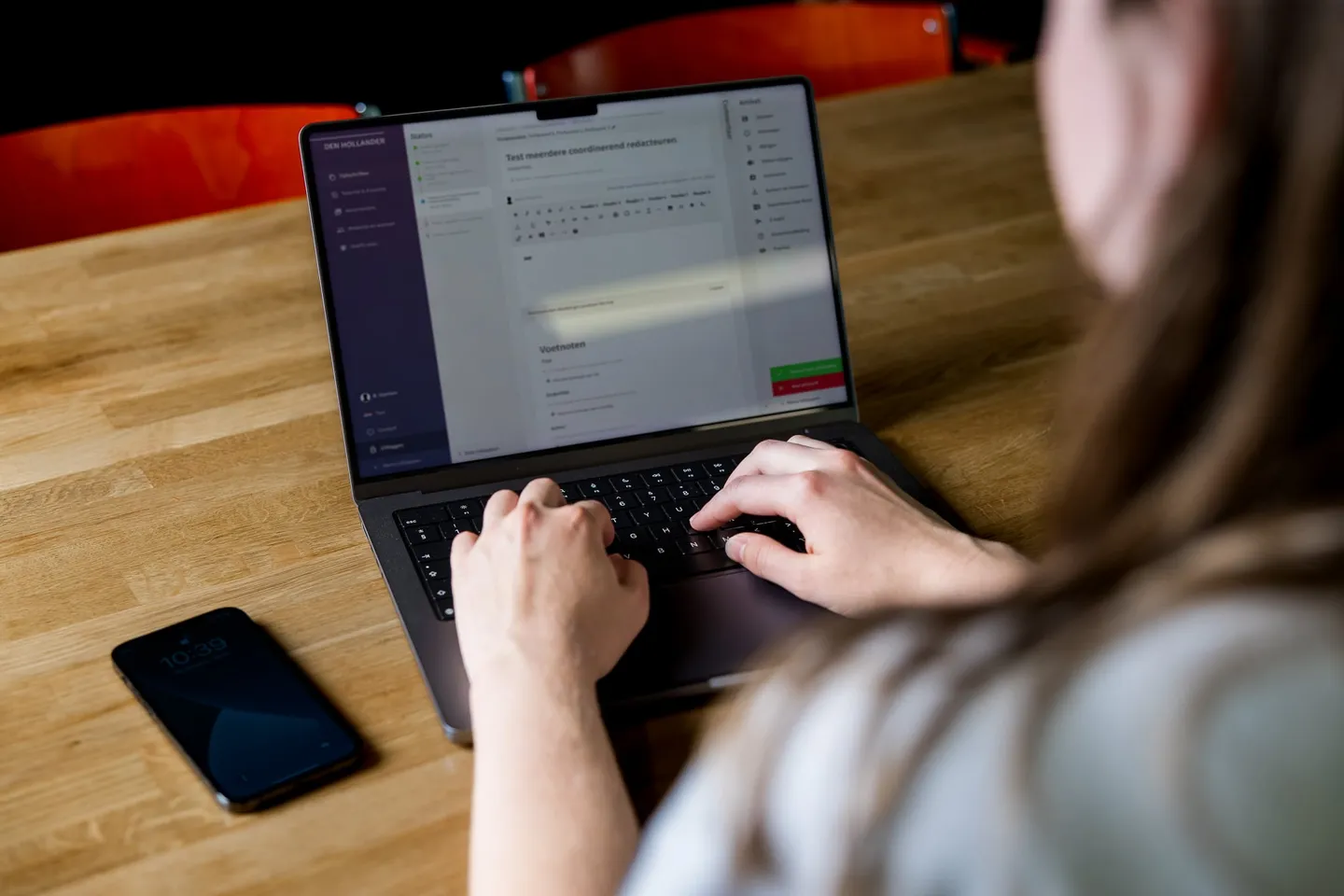 Een collega van Dutch Coding Company werkt op een laptop aan een houten tafel